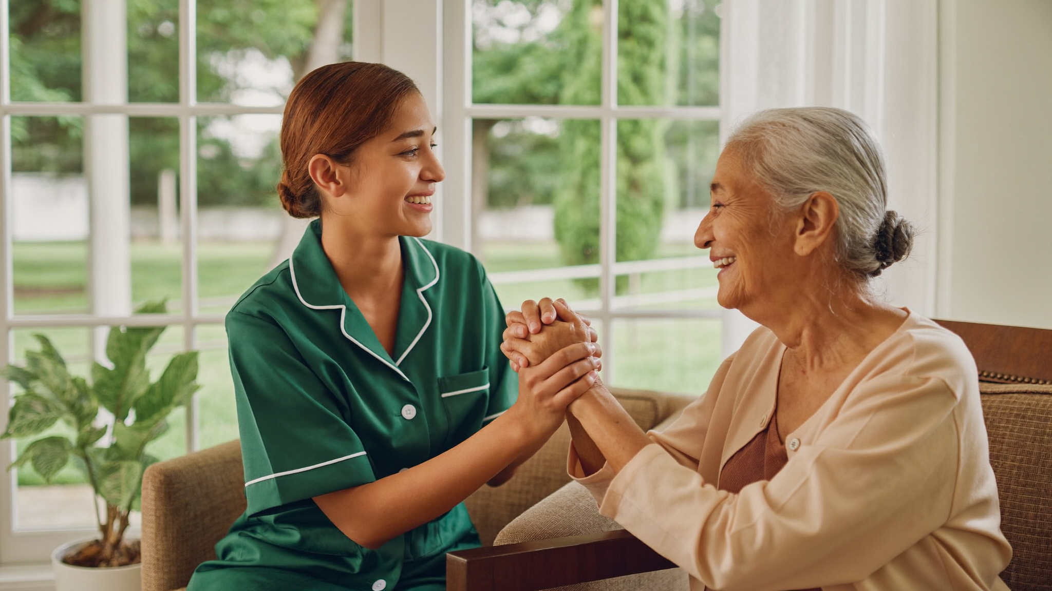 Our mission - caregiver holding hands with an elderly woman at home